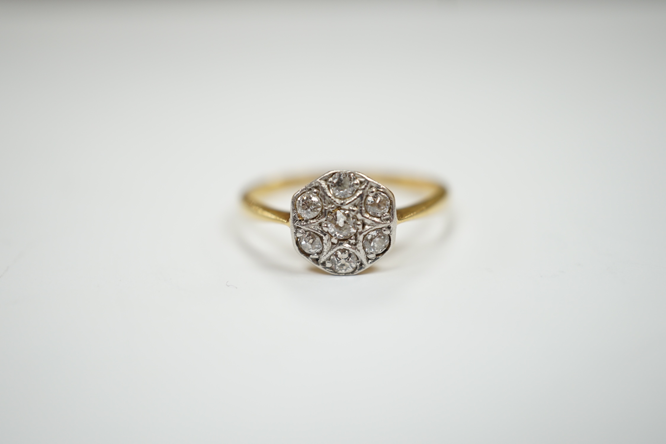 A 1920's 18ct, plat and seven stone diamond set cluster ring, size K, gross weight 2.2 grams.